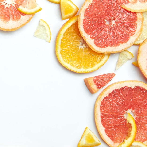 Cerca de rodajas de limón, naranja y pomelo cítricos frescos sobre superficie blanca