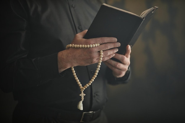 Foto cerca del sacerdote católico sosteniendo la oración de lectura de la biblia y el rosario