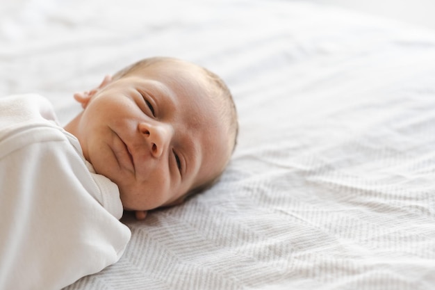 Cerca de sonriente caucásico peludo brunet lindo bebé recién nacido mirando cameraone o niño de dos semanas