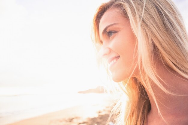 Foto cerca de una sonriente rubia mirando a la playa