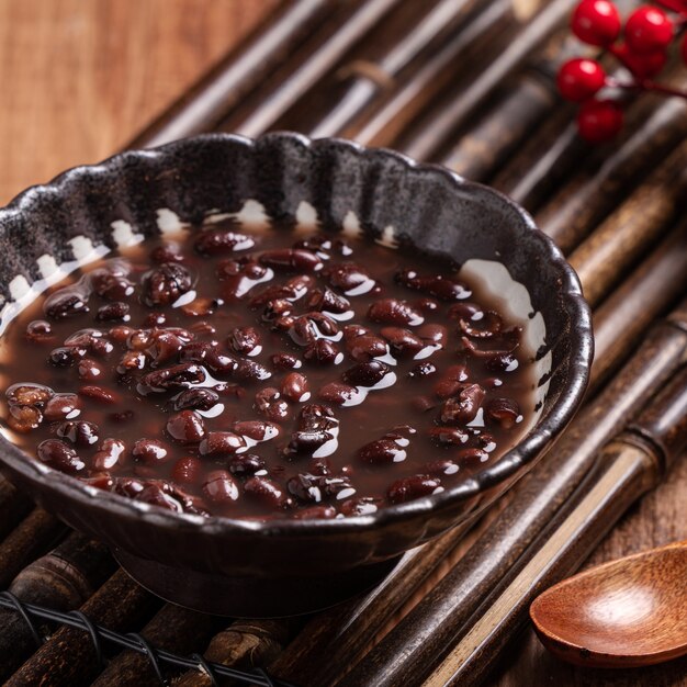 Cerca de la sopa de frijoles rojos adzuki en un recipiente sobre fondo de mesa de madera para comer.