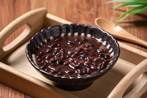 Cerca de la sopa de frijoles rojos adzuki en un recipiente sobre fondo de mesa de madera para comer.