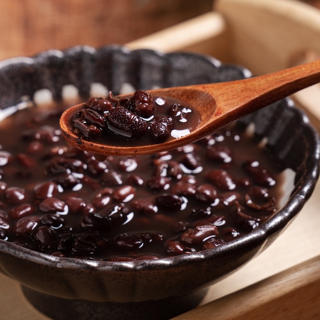 Cerca de la sopa de frijoles rojos adzuki en un recipiente sobre fondo de mesa de madera para comer.