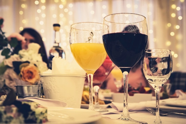 Foto cerca de stemwares en una mesa de restaurante servida en una ocasión festiva. vasos llenos de vino tinto y jugo en una mesa de restaurante en una cena formal. mesa festiva servida en una boda.