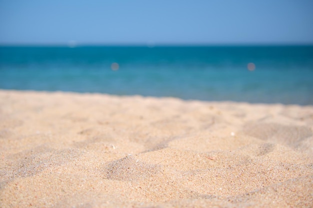 Cerca de la superficie de arena amarilla limpia que cubre la playa con agua de mar azul en el fondo. Concepto de viajes y vacaciones.