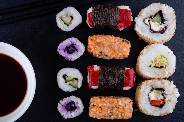 Cerca de sushi con salmón y jengibre en hojas verdes sobre fondo negro