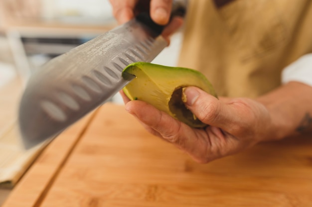 Cerca de sushi vegano maestro de sushi asiático de gran angular rebanar aguacate con cuchillo