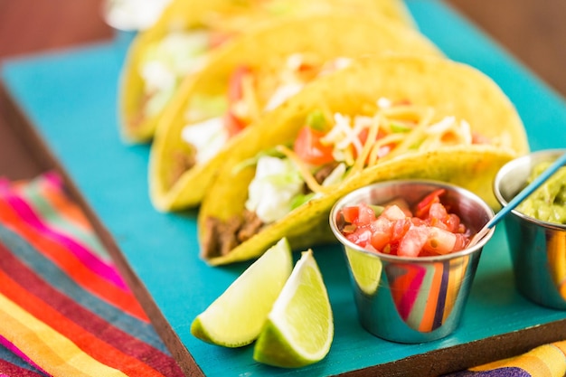 Cerca de tacos de carne fresca en cáscara de taco de maíz amarillo duro con crema agria y queso rallado.