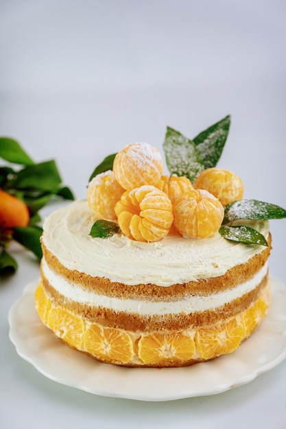 Cerca de tarta de cítricos con mandarina fresca y hojas verdes