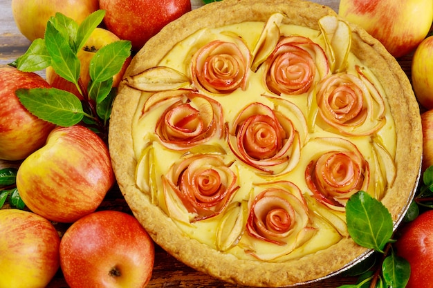 Cerca de tarta de manzana con manzana en forma de rosa decorada y manzanas frescas. Vista superior.