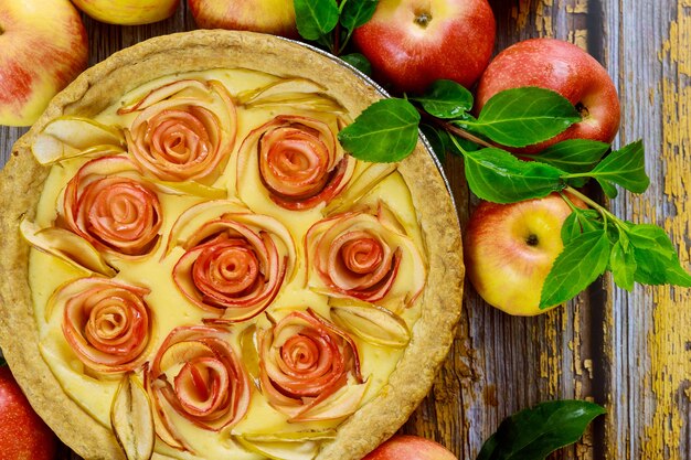 Cerca de tarta de queso con manzana en forma de rosa decorada y manzanas frescas. Vista superior.