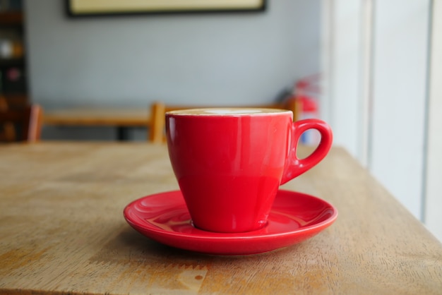Cerca de la taza de café de color rojo en la mesa del café