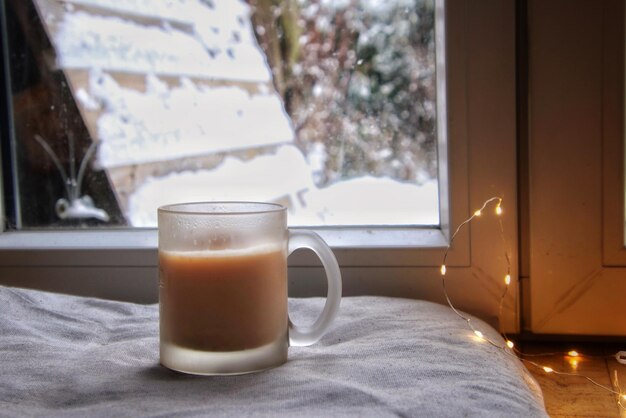 Foto cerca de la taza de café contra el fondo invernal junto a la ventana