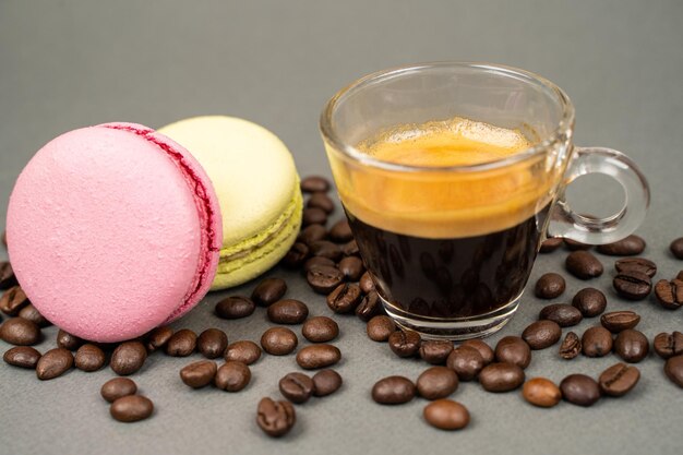 cerca de la taza de café esparcidos granos de café y galletas de macarrones