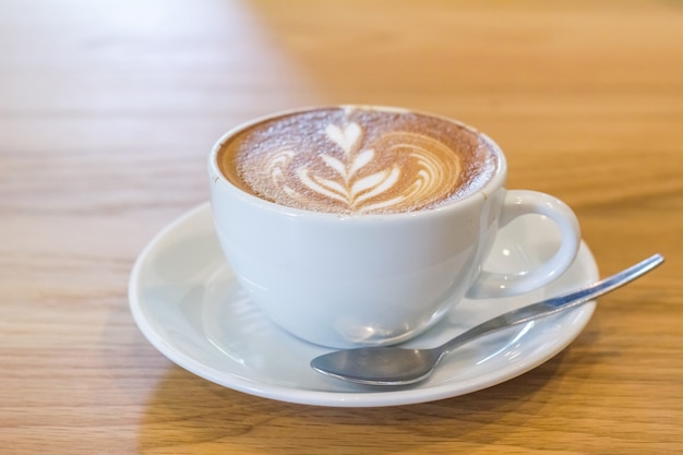 Cerca de la taza de café con leche y café con leche colocado en los pisos de madera