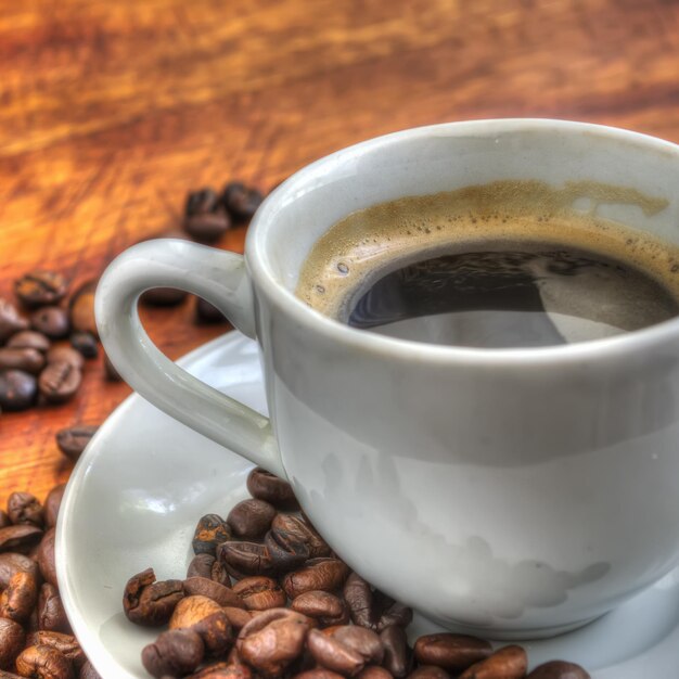 Cerca de una taza de café en una mesa de madera rodeada de frijoles