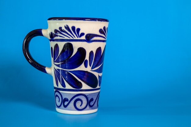 De cerca una taza de Talavera con un fondo azul.