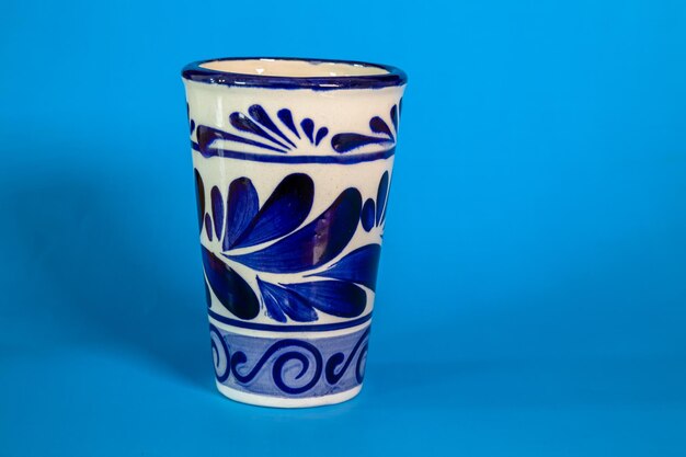 De cerca una taza de Talavera con un fondo azul.