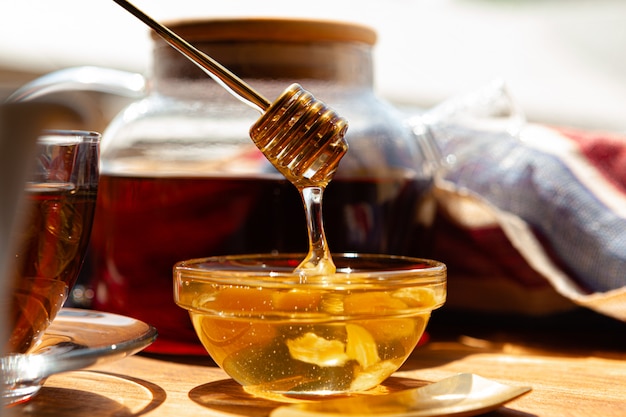 Cerca de la taza de té de cristal con miel