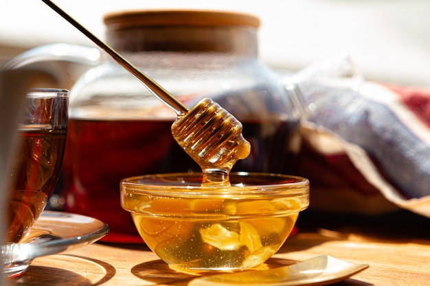 Cerca de la taza de té de cristal con miel