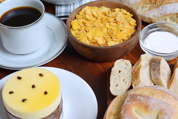 Cerca de la torta de fruta de la pasión, tostadas, café, yogur, cereales.