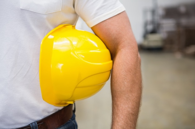 Cerca del trabajador del almacén sosteniendo un casco