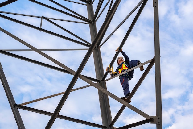 Cerca de los trabajadores que usan arneses de seguridad están trabajando en torres de alta tensión para inspección y mantenimiento en estaciones de torres de alta tensión