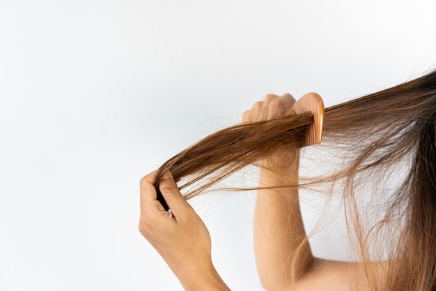 Cerca de la triste joven asiática con su cabello enredado. Aislado sobre fondo blanco, espacio de copia