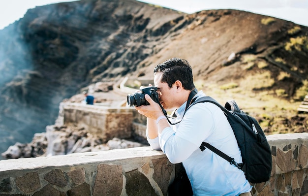 Cerca de turista tomando fotos en un mirador volcánico Un turista con una cámara de fotos tomando fotos en un mirador Hombre aventurero con su cámara tomando fotos en un mirador