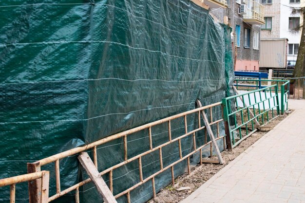 Cerca verde del sitio de construcción cerca de la acera