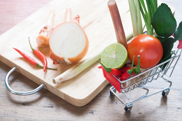 Cerca de verduras frescas en carrito de la compra en la mesa de madera