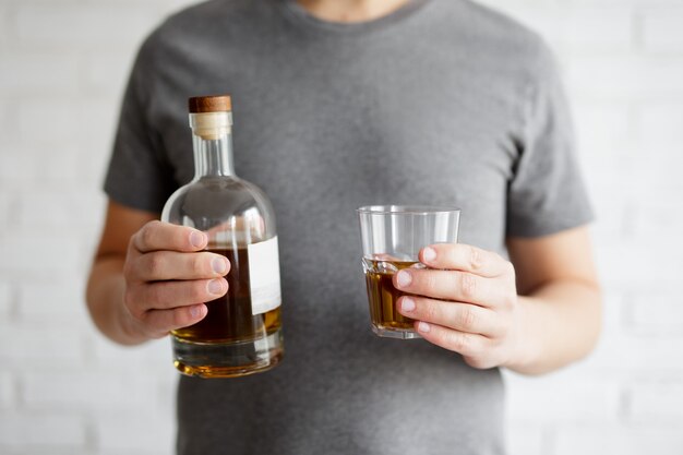 Foto cerca de vidrio y botella de whisky en manos masculinas