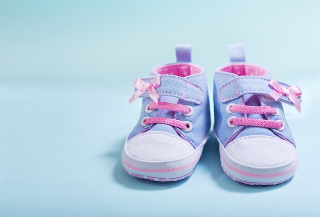 Cerca de zapatillas de bebé sobre fondo azul.