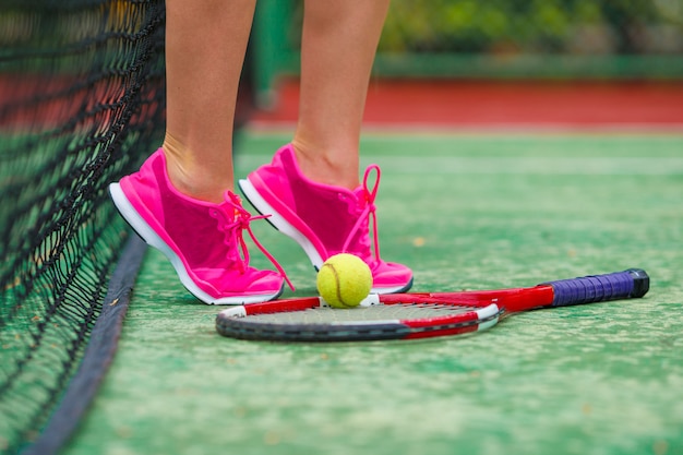 Cerca de zapatillas de deporte cerca de la raqueta de tenis y la pelota