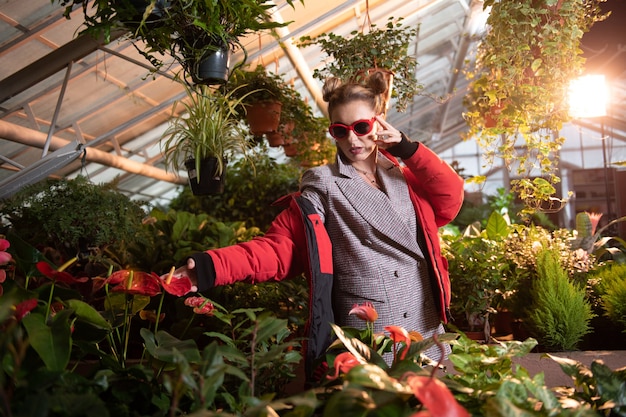 Cercanía a la naturaleza. Bonita mujer guapa con una chaqueta roja mientras mira la flor