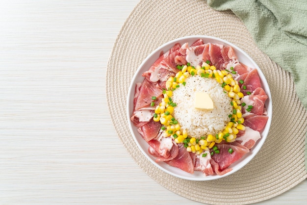 Cerdo fresco crudo en rodajas con arroz y maíz en un plato y listo para cocinar