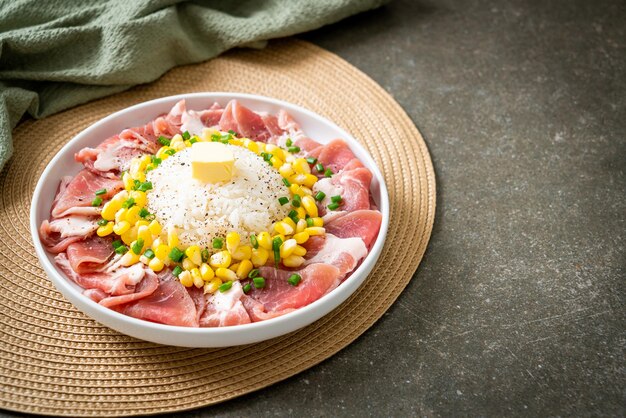 Cerdo fresco crudo en rodajas con arroz y maíz en un plato y listo para cocinar