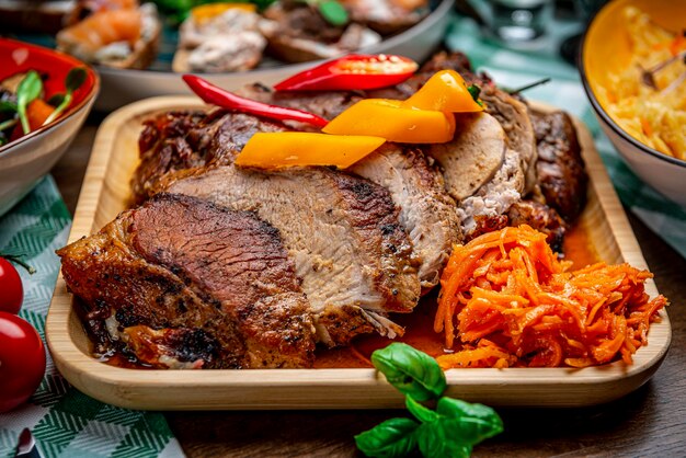 Cerdo jugoso asado con verduras en un plato de madera