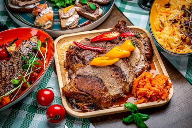 Cerdo jugoso asado con verduras en un plato de madera