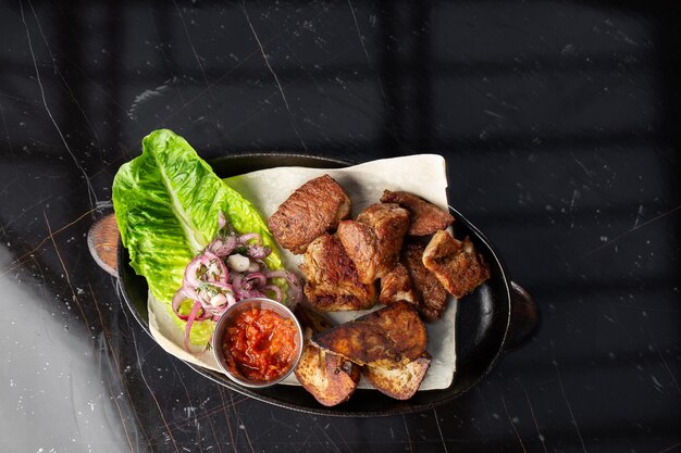 Cerdo a la parrilla con papas doradas al horno servido con salsa roja sobre un fondo oscuro Deliciosa Receta Filete de Cerdo Cocido