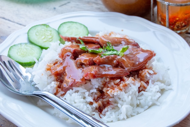 Cerdo rojo con arroz y pepino en una placa.