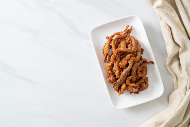 Cerdo secado al sol en un plato blanco al estilo de la comida asiática