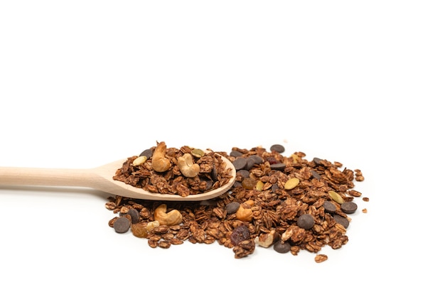 Cereais de granola de chocolate com nozes em uma colher de pau. Isolado no bacckground branco.