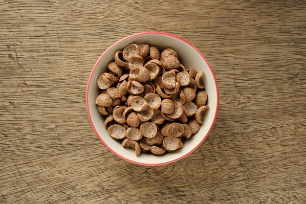 Cereais de pequeno-almoço em uma tigela no pano de fundo de madeira