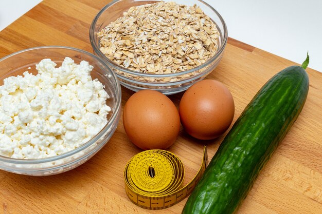 Cereais, fita métrica, requeijão fazenda ovos ovos cenoura perto sobre fundo branco. dieta saudável gordura livre eco esportes nutrição