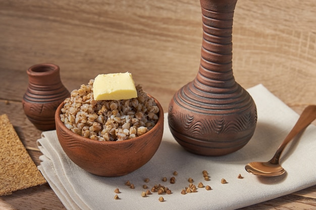 Cereal de alforfón cocido en un recipiente de arcilla marrón en la mesa de madera. grano sin gluten para una dieta saludable