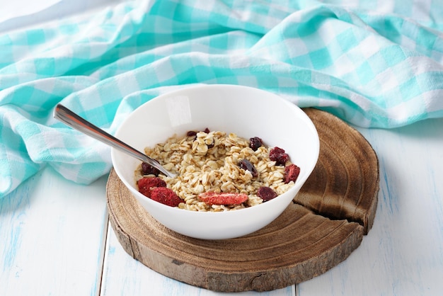 Foto cereal de avena con bayas y miel en un plato blanco sobre una mesa de madera.