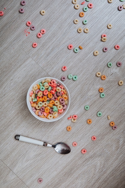 Cereal de colores en un cuenco con cuchara en el suelo.