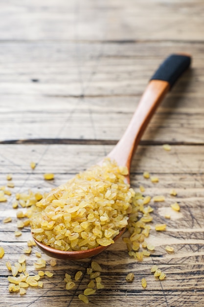 Foto cereal cru seco turco tradicional do bulgur em uma colher de madeira.