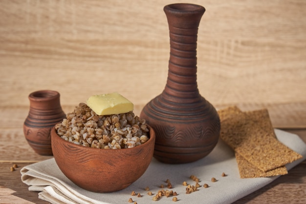 Cereal de trigo sarraceno cozido na tigela de barro marrom na mesa de madeira. grãos sem glúten para uma dieta saudável